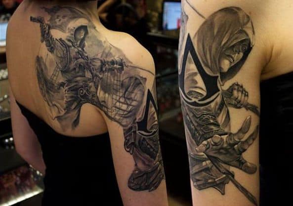 Tatuaż Assassin’s Creed na barku i ramieniu Rozbudowany czarno-szary tatuaż Assassin’s Creed obejmujący bark i ramię